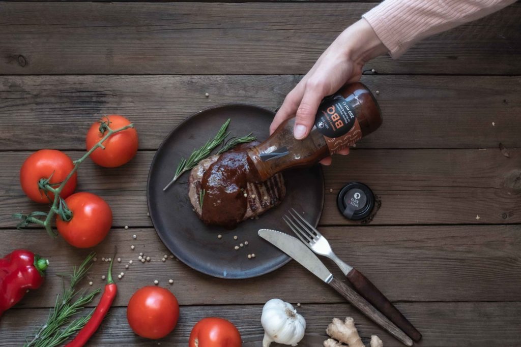 Hand gibt regionale BBQ Sauce aus Leipzig über Steak